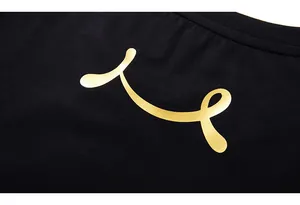 Detail of black cotton T-shirt featuring a matte gold metallic abstract curved print