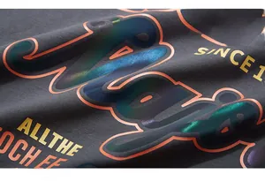 Macro shot of iridescent reflective letter print on dark grey cotton T-shirt fabric