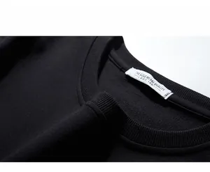 Detailed close-up of ribbed crew neck and printed size label on black cotton sweatshirt