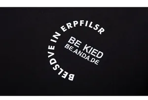 Detailed close-up of white letter embroidery and print on black cotton sweatshirt fabric