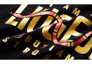 Close-up of gold foil lettering and red coral snake print on black cotton t-shirt