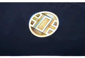 Macro shot of metallic golden circular logo printed on navy blue cotton t-shirt fabric