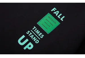 Detail of mint green lettering and woven tag on black cotton sweatshirt fabric