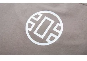 Close-up of white geometric logo printed on heavy-duty taupe cotton fabric T-shirt