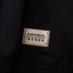 Close-up of black streetwear hoodie featuring a premium stitched AIRGINOL brand label