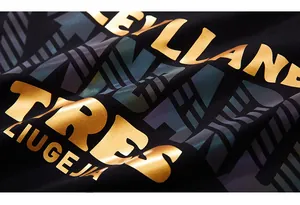 Détail macro du lettrage doré métallique et imprimé réfléchissant sur un t-shirt noir