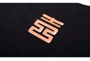Detail of premium black cotton T-shirt featuring a large orange geometric matte logo