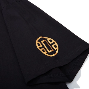 Gros plan d'une manche de T-shirt noir en coton avec motif géométrique doré de qualité