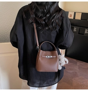 Brown litchi leather bucket bag detail with plush bunny charm and silver twist lock