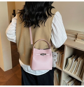 Pink lychee grain leather bucket bag with a plush charm shown in a lifestyle setting