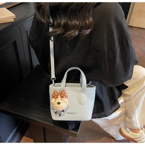 Detail of light blue lychee textured tote bag with cute plush bear charm on its side
