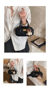 Detail of black bowling bag with lychee texture, golden logo plate and bear charm