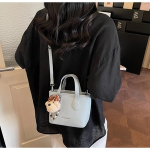 Close-up of light blue pebble leather mini bag with cute teddy bear charm on model