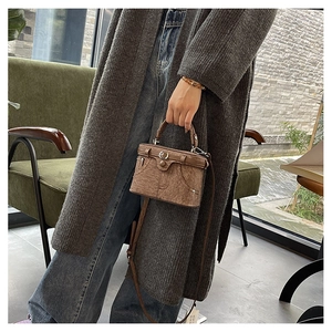 Detail view of a vintage brown box bag with denim-style pocket and stitching on grey knit