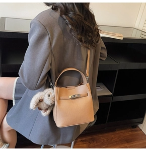 Close-up of a light brown lychee grain bucket bag featuring a plush bunny and metal lock