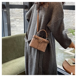 Detail of vintage brown textured box bag with metal buckle and top handle in scene