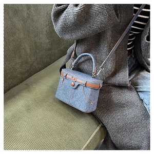 Detail of creative denim box bag with vintage buckle and stylish jean pocket elements