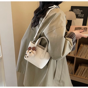 White lychee leather bucket bag detail with plush bear charm and adjustable strap