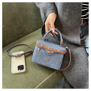 Close-up of denim handbag with jeans-style pockets, buttons and leather piping detail