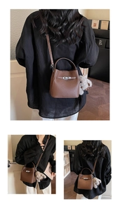 Detail of brown lychee grain leather bucket bag with silver twist lock and bunny charm