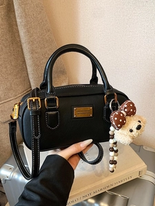 Retro black bowling bag with white stitching, dual handles, and a cute teddy bear charm