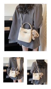 Detail view of white lychee grain bucket bag featuring a silver lock and plush bunny charm