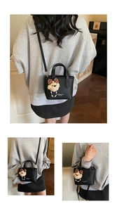 Detail of black litchi grain leather mini bucket bag with cute teddy bear charm