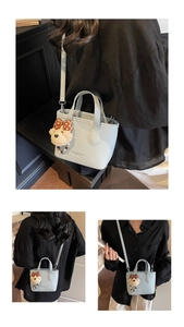 Detail of light blue leather bucket bag with plush bear charm and detachable strap