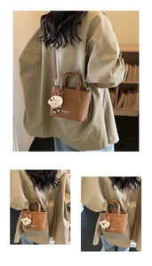 Close-up of brown textured leather bucket bag with teddy bear charm and logo print
