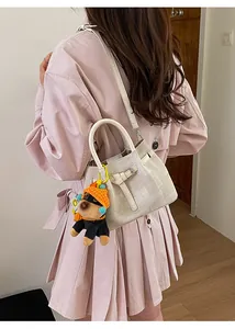 Beige karierte Canvas-Beuteltasche mit Hundeanhänger getragen zum rosa Trenchcoat-Mantel