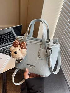 Light blue pebbled leather bucket bag with top handle and plush bear charm