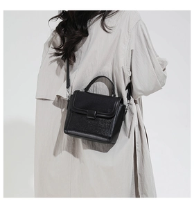 Model wearing a black pebble leather crossbody bag with silver hardware and top handle