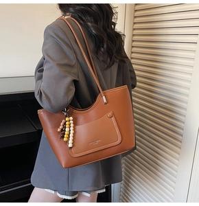 Brown lychee texture leather tote bag detail with decorative pocket and beaded tassel