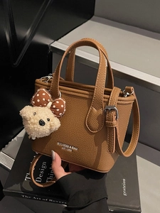 Brown litchi grain bucket bag with adjustable strap and plush dog charm accessory