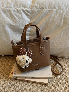 Brown litchi grain leather bucket bag with top handle and teddy bear charm accessory