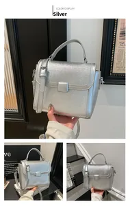 Detail of silver flap handbag with metallic texture and adjustable crossbody strap