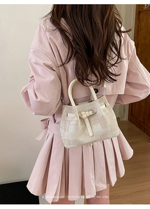 Detail view of a beige textured fabric bucket bag with leather handles and retro vibes