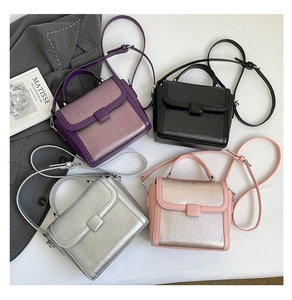 Detail view of four minimalist square bags in purple, black, silver, and pink leather