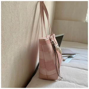 Pink striped canvas tote bag with a cute cat charm leaning against a textured wall