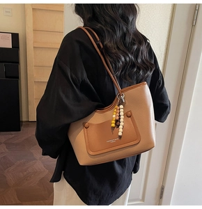 Detailed back view of model wearing a brown lychee pattern tote bag with color-block pocket