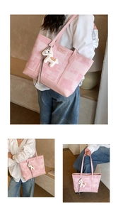 Detail of pink checkered large tote bag with horse charm in soft indoor lighting