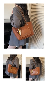 Close-up of brown textured tote bag featuring a beaded charm and fashion logo print