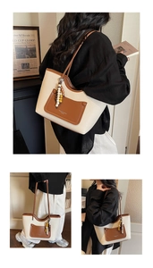 Detail view of cream tote bag with brown leather trim and colorful beaded charm