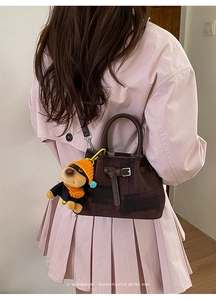 Detail der Retro-Karo-Beuteltasche mit süßem Hunde-Plüsch-Anhänger und Ledergriff