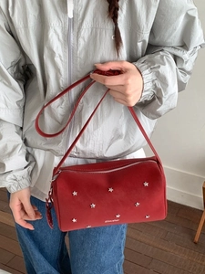Red suede crossbody bag with silver star rivets and adjustable strap shown on model