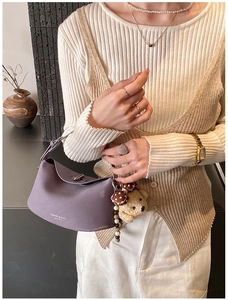 Détail d'un sac à main en cuir violet avec texte de mode et breloque ours peluche