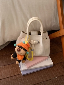 Elegant white woven bucket bag with leather handle and cute cartoon dog charm accessory