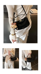 Detail of black leather half-moon bag with golden twist lock and teddy bear charm