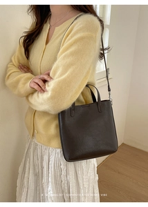 Sac seau en cuir mat marron foncé porté par un mannequin pour un look rétro et minimaliste