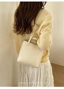 Sac à bandoulière minimaliste crème porté par un mannequin pour un style rétro chic